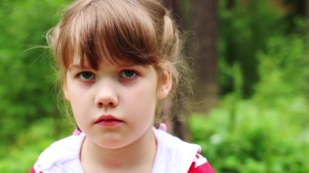 Маленькая симпатичная девочка гримасы в летнем парке. Закрыть вид — стоковое видео