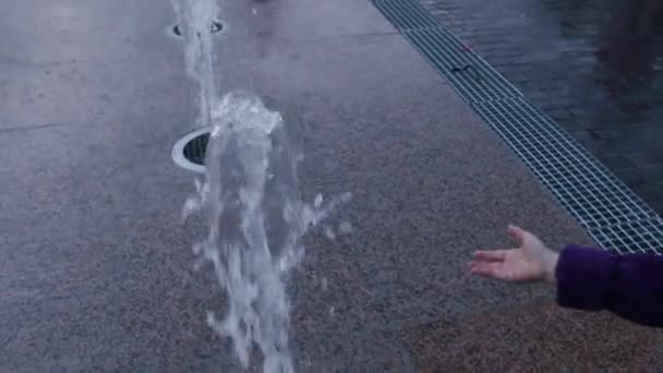 Malá holčička se dotýká vody pouliční kašna na večer — Stock video
