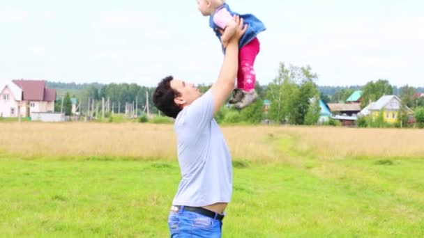 Щасливий батько кидає свою маленьку дочку на луг — стокове відео