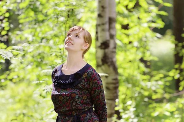 Young beautiful woman looks up and dreams in summer sunny forest — Stock Photo, Image