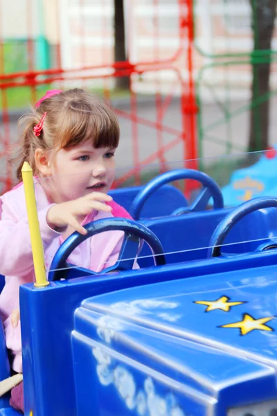 Little pretty girl rides on bright car in amusement park — Stock Photo, Image