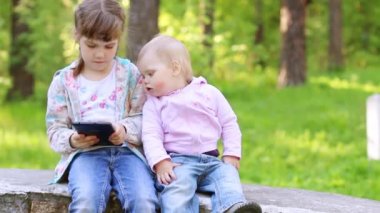 Küçük kız tablet Pc ile çalış ve diğer küçük kız yaz parkta baktığı
