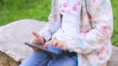 Küçük kızın tablet Pc taş yaz Park'ta üzerinde oynamaktan eller