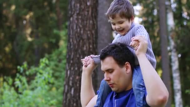 Young handsome man plays with his little son in summer park — Stock Video