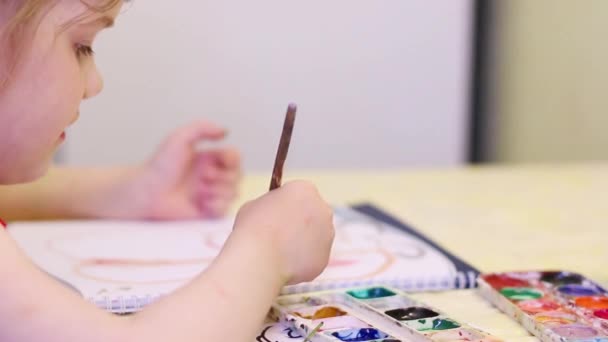 Niña pintando en cuaderno en la mesa. De cerca. — Vídeo de stock