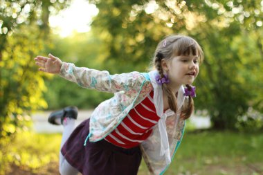 Güzel küçük kız örgü ile kuş güneşli gün gösteriyor.