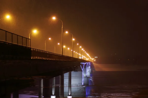 Мост с подсветкой и фонарями во время снегопада зимой — стоковое фото