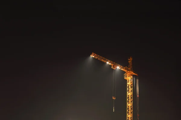 Ψηλό κίτρινος γερανός με φωτισμό σε εργοτάξιο — Φωτογραφία Αρχείου