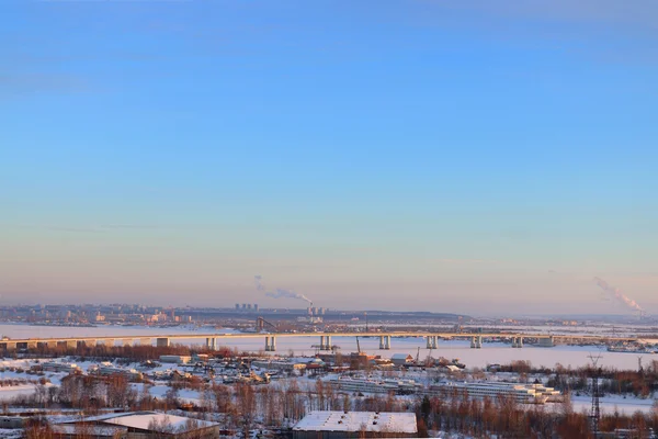 Мост через замерзшую реку и панорамный вид на город — стоковое фото