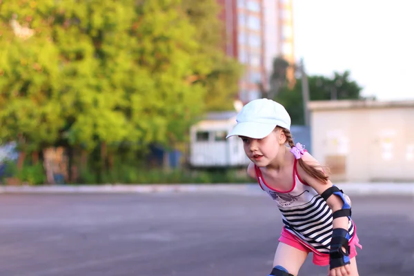Glückliches kleines Mädchen mit Mütze Rollschuh auf Asphalt Outdoor — Stockfoto