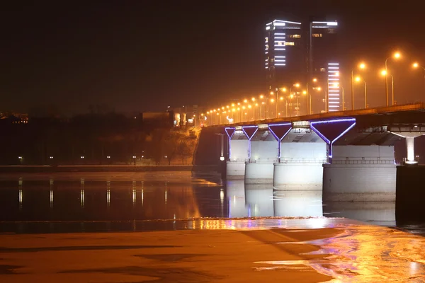 Мост и высокое здание с освещением и льдом реки — стоковое фото