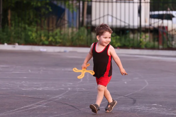 Feliz niño guapo con boomerang corre en la noche de verano — Foto de Stock