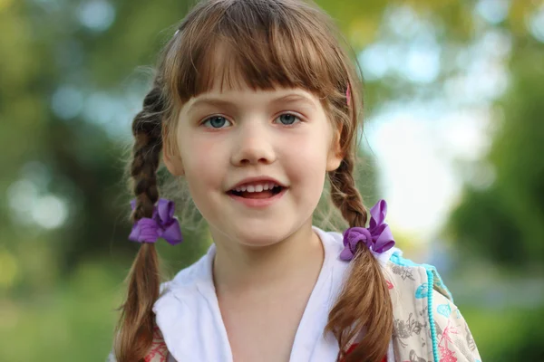 Close up portrait of pretty smiling little girl with braids outd — Stock Photo, Image