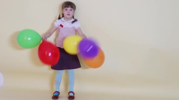 Niña sostiene y lanza en el estudio globos de colores — Vídeo de stock