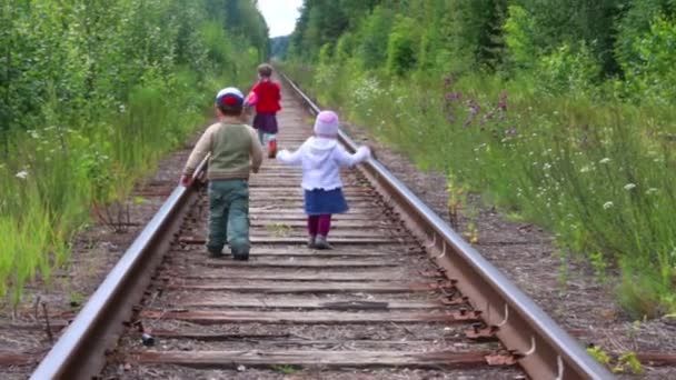 Atrás de tres niños caminando en el ferrocarril en el bosque en el día de verano — Vídeos de Stock