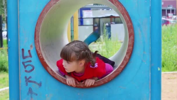 Kleines süßes lächelndes Mädchen spielt in Röhre auf Spielplatz — Stockvideo