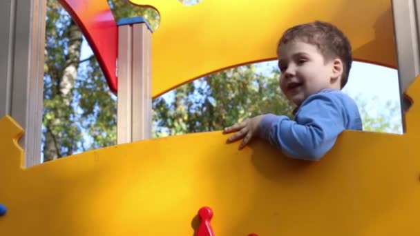 Девочка и мальчик веселятся на детской площадке в осенний день — стоковое видео