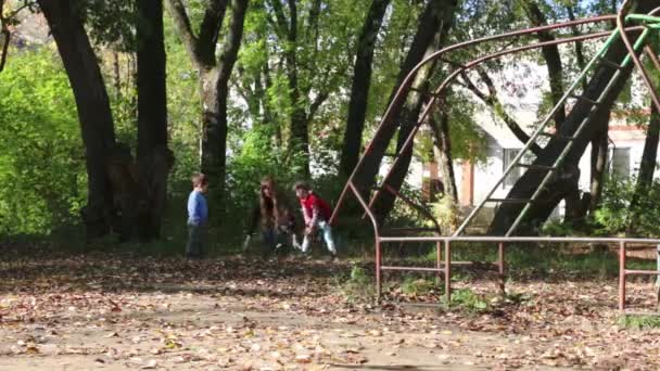 Klein meisje en jongen met zijn moeder overgeven bladeren in de herfst dag — Stockvideo