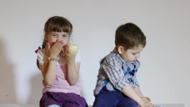 Primer plano de niño y niña sentados en la caja y comer manzanas — Vídeos de Stock