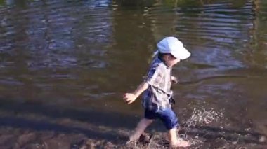 Küçük çocuk su birikintisi kız yakın kenarında suyla çalışıyor