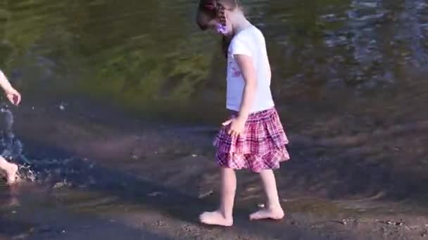 Kleine jongen loopt op water op de rand van de vijver in de buurt van meisje lopen op de rand van de vijver — Stockvideo