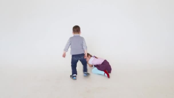 Niña y niño jugando en la pared blanca en el estudio — Vídeos de Stock