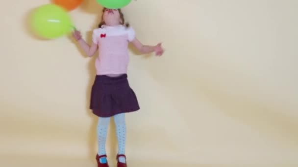 Petite fille mignonne tient et vomit des ballons colorés — Video