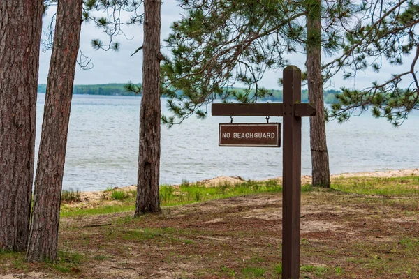 Señal que dice que no hay guardia de playa designada playa de natación en el campamento estatal —  Fotos de Stock