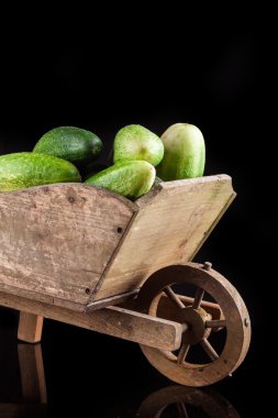 salatalık ve kabak siyah bir zemin üzerine ahşap bir tekerlek