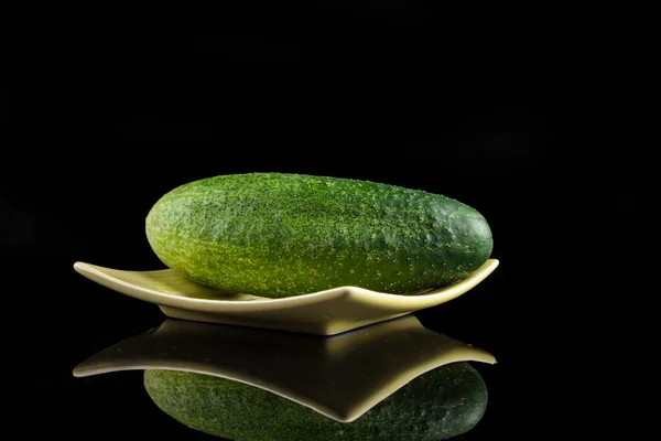 Pepino en un plato sobre un fondo negro —  Fotos de Stock