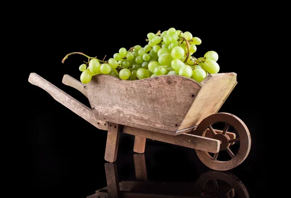 Bílé víno hrozny na černém pozadí v dřevěném kole — Stock fotografie