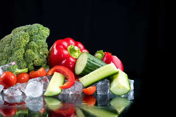 氷のキューブと砕いた氷と黒の背景に野菜 — ストック写真