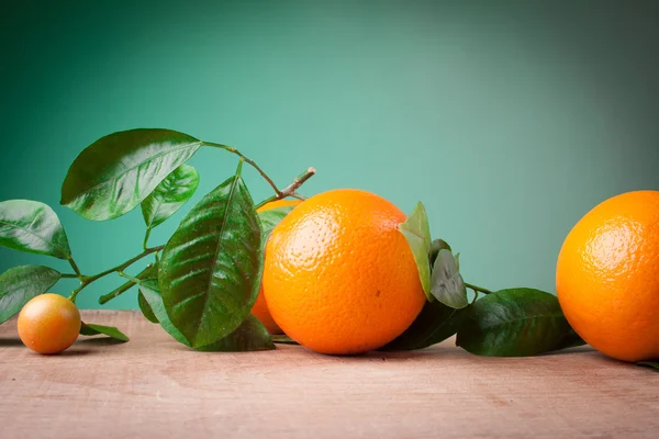 Oranges with shoots on a wooden table — Stock Photo, Image