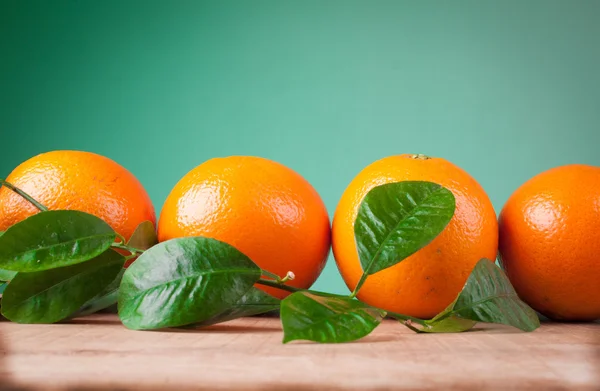 Oranges with shoots on a wooden table — Stock Photo, Image