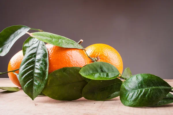 Oranges with shoots on a wooden table — Stock Photo, Image