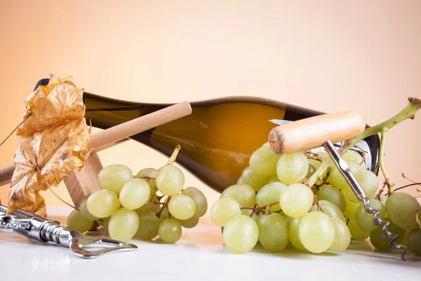 Bottle of white wine and grapes on a wooden table — Stock Photo, Image