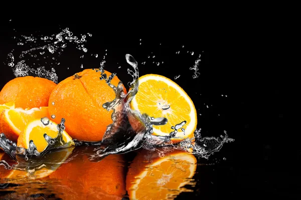 Oranje vruchten en spatten water — Stockfoto