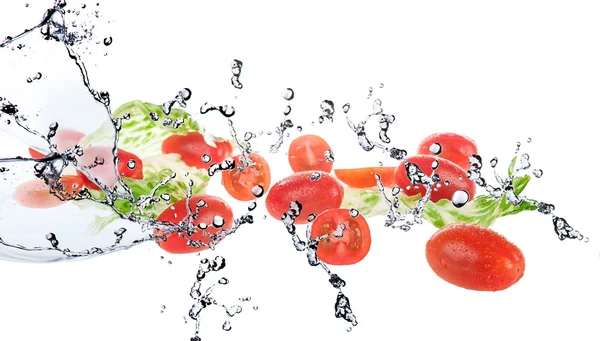 Salada com tomates isolados em fundo branco e água salpicada — Fotografia de Stock