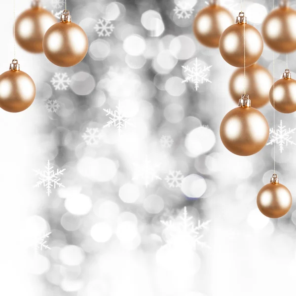 Goldener Weihnachtsschmuck auf silbernem Hintergrund mit Flocken — Stockfoto