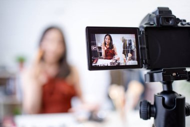 Kamera bir video kaydediyor. Güzel bir Asyalı blogcu size odada nasıl makyaj yapılacağını öğretiyor..