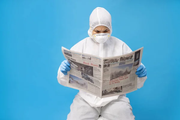 手袋やマスクで保護服のアジアの女性 彼女はCovid 19に関する新聞を読んでいます — ストック写真
