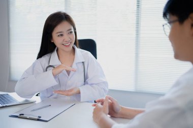 Asyalı kadın doktor hastanedeki hastalara bir şeyi analiz ediyor ve açıklıyor..