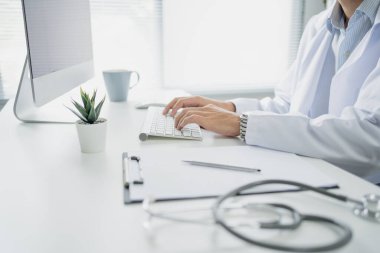 Doktor ofisteki masada oturmuş bilgisayarla çalışıyordu..