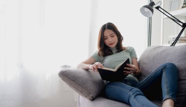 İyimser bir kadın mutludur. Kanepeye oturur ve kitap okur..