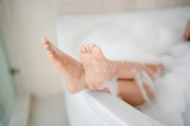 Banyodaki kadın ayakları. Vücudunu temizlemek için sabunla duş alıyordu..