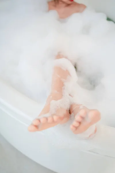 Woman's feet in the bath. She is taking a shower in the bathroom.