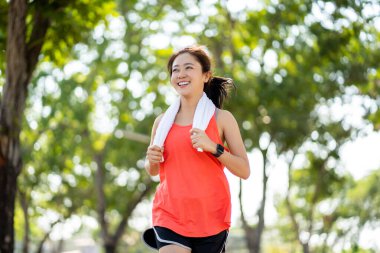 Parkta koşan ve gülümseyen güzel Asyalı koşucuyu yakından çek..