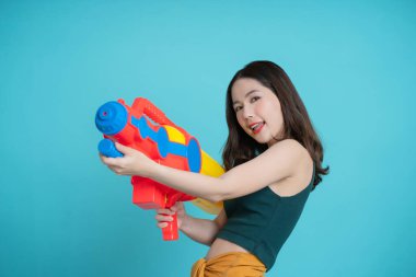 Asyalılar, mavi arka plandaki bir stüdyoda Songkran festivali için su tabancası kullanıyorlar..