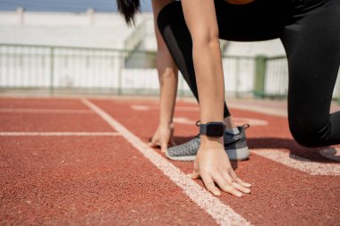 Stadyumdaki koşucu başlangıç pozisyonunda ve elleri çizgide. Başlama çizgisinde eller.
