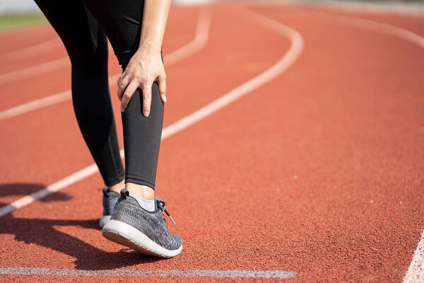 Молодая азиатка-бегунья получила травму ноги после пробежки на открытом воздухе. У неё болит нога..